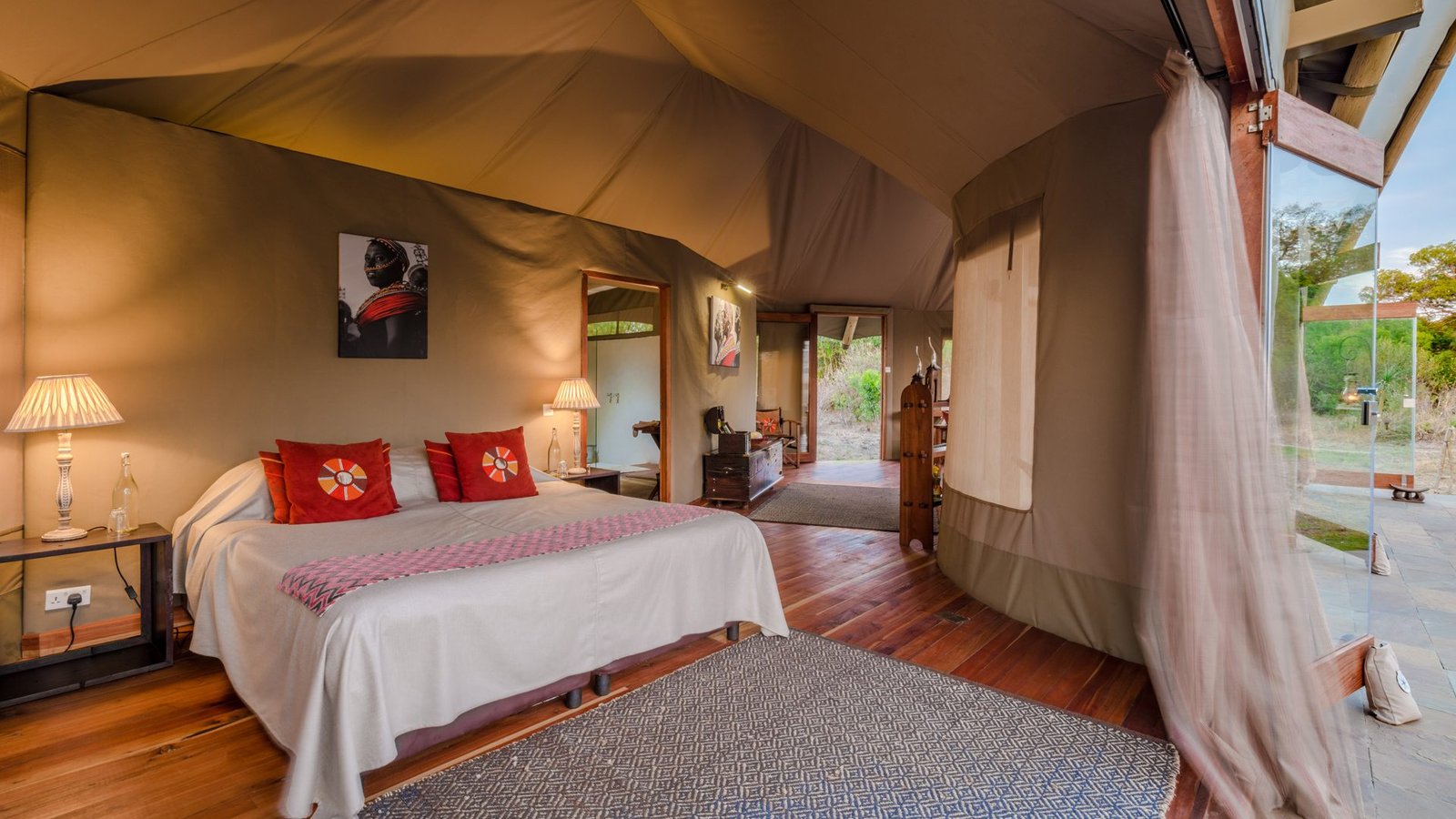 Interior of a luxury tented suite with king bed, timber floors and warm lamps