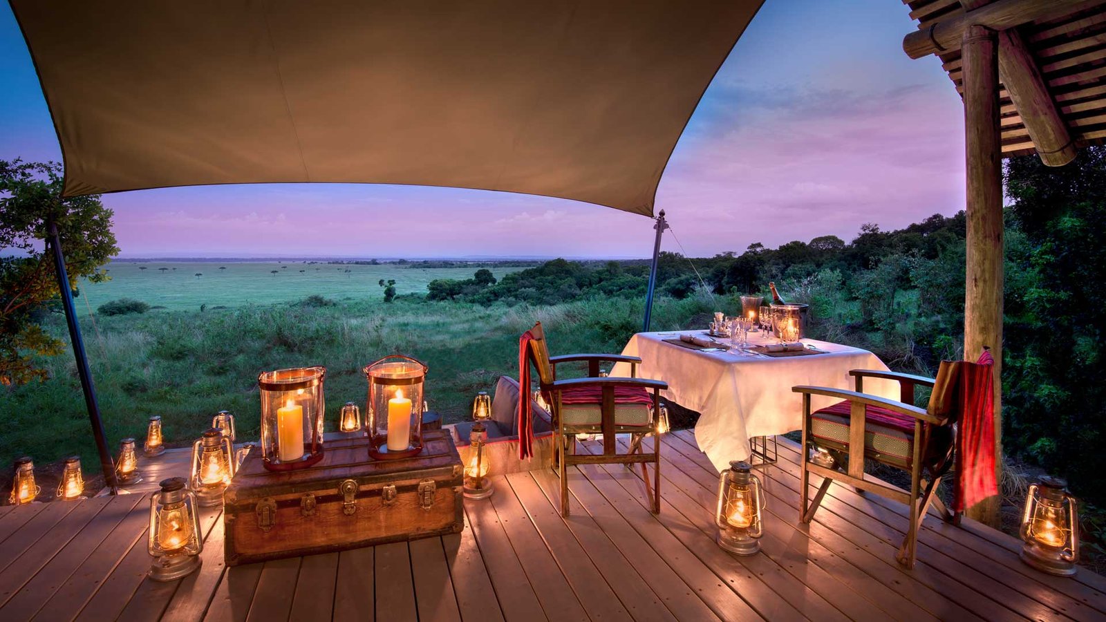 Lantern-lit outdoor dining table overlooking the Masai Mara at night