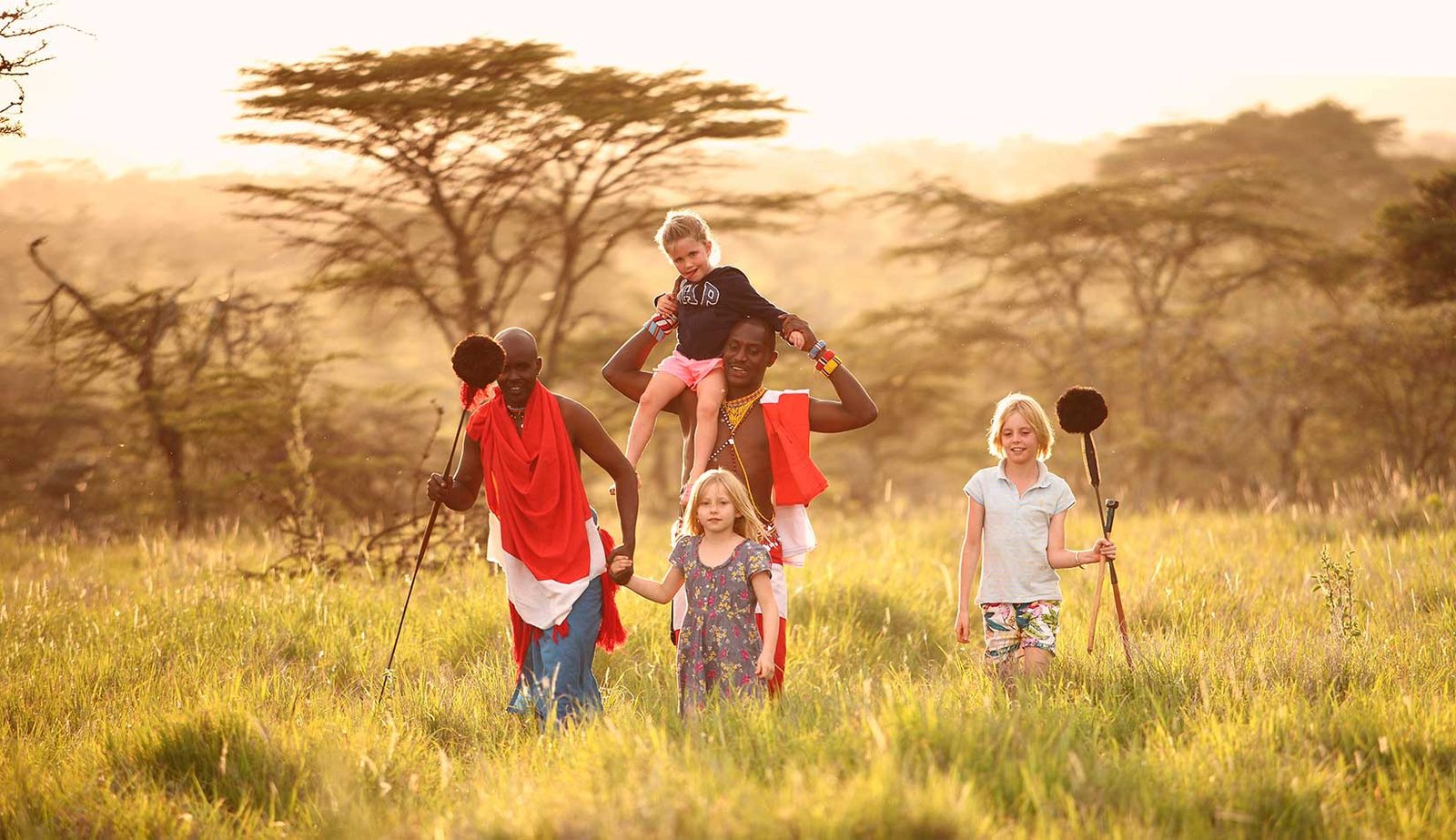 Family walking with Maasai guides at sunset